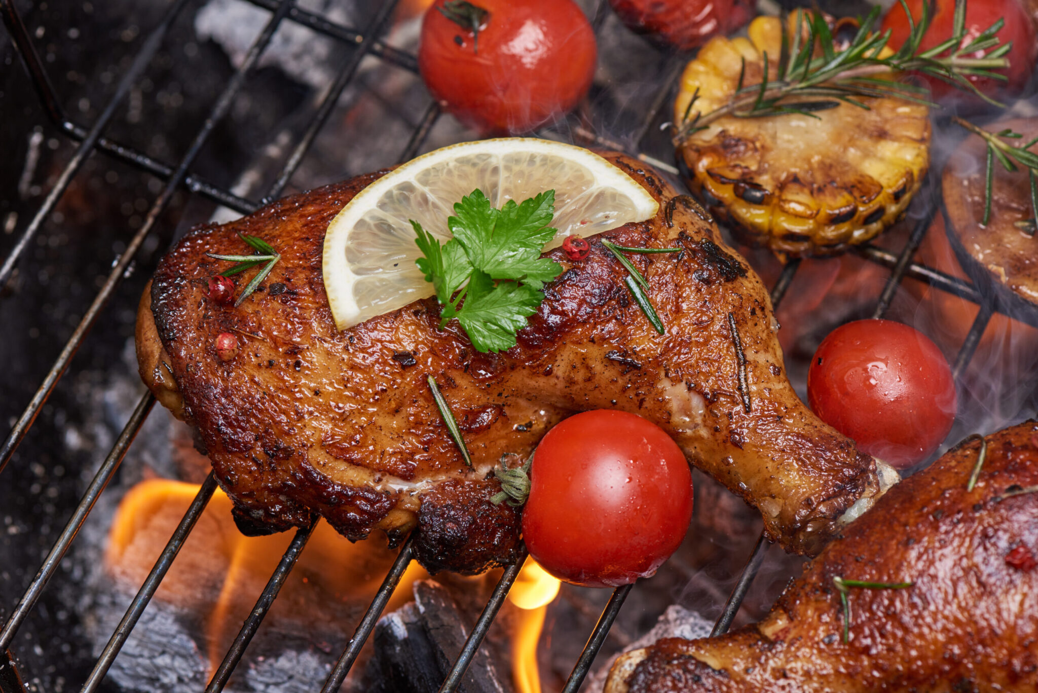 Grilled chicken legs on the flaming grill with grilled vegetable